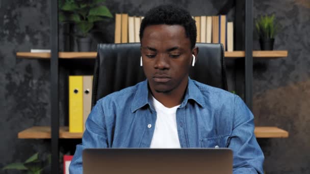 Pensativo hombre afroamericano trabaja para el ordenador portátil y piensa en la oficina — Vídeo de stock
