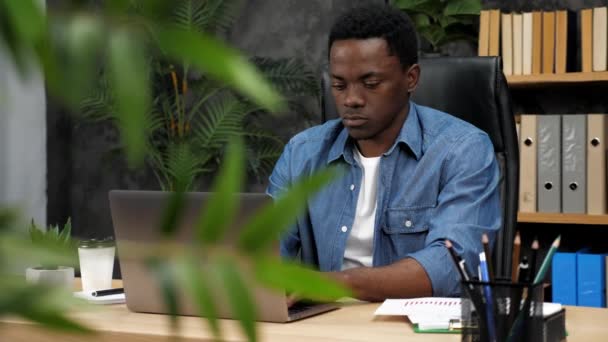 Взрослый афроамериканец фрилансер работает на ноутбуке, печатая текст на клавиатуре — стоковое видео