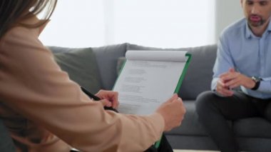 Arkaya bakan kadın psikoloğu not alıyor hastayı dinliyor