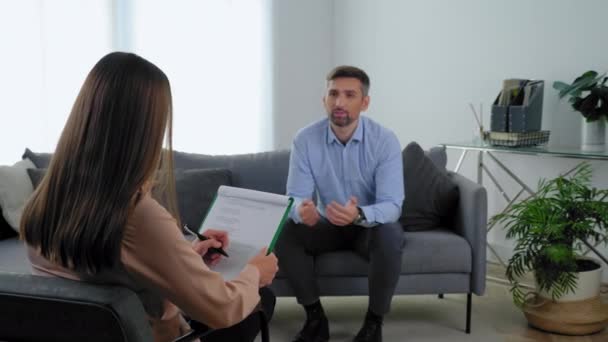 Paciente homem sorridente desfocado com problemas de saúde mental conversando com o terapeuta — Vídeo de Stock