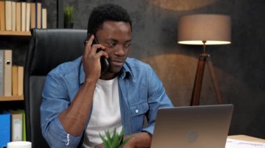 Afrikalı Amerikalı işadamı üst düzey yöneticilerle cep telefonundan konuşuyor.