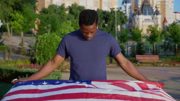 Fotoaparát zoom v patriot Afroameričan muž drží americkou vlajku a vypadá fotoaparát — Stock video