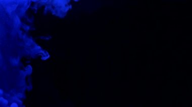 Slow motion blue ink acrylic paint mixing in water, swirling softly underwater