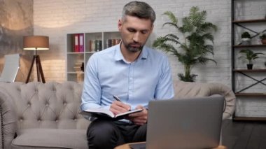 Borsacı adam yatırımcıyı internetten dinliyor, not defterine notlar yazıyor.