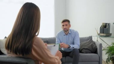 Ruh sağlığı sorunları olan bir adam kanepede oturup terapistle konuşuyor.