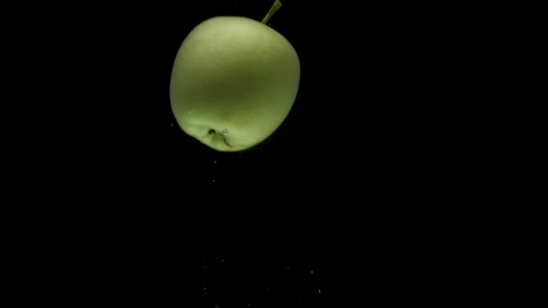 Slow motion one green apple falling into transparent water on black background — Stock Video