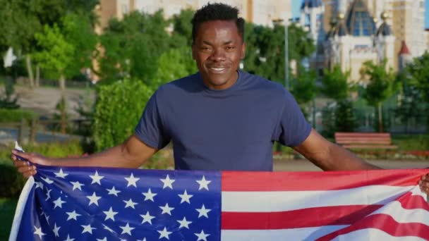 Camera zoom in patriot smiling Afro-American man holding American flag — Videoclip de stoc