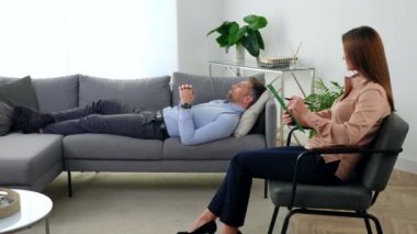 Sandalyede oturan kadın psikolog psikoterapi seansında hastayı dinliyor.
