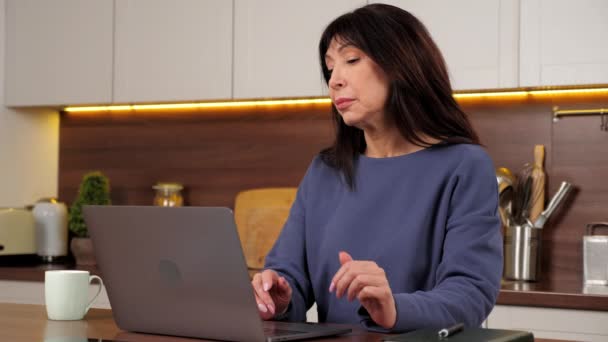 La distancia de la mujer de negocios trabaja para el ordenador portátil que bebe té de la taza en la cocina casera — Vídeos de Stock