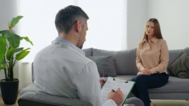 Psikoterapist adam. Hastanın klinikteki not defterine not aldığını dinle.