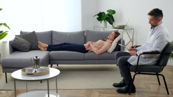 Mulher depressiva com problemas de saúde mental deitada no sofá conversando com o terapeuta — Vídeo de Stock