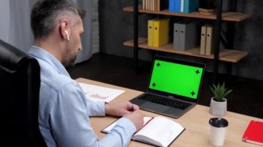 İnsan borsacısı not defterine not alır. Yeşil ekranlı dizüstü bilgisayar kullanır.