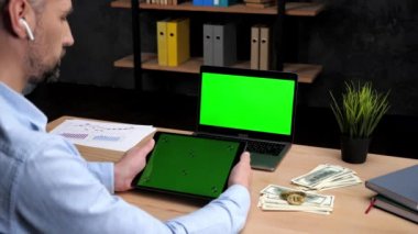 Adam borsacısı, tablet yeşili kaydırıyor. Yeşil ekranlı laptop.