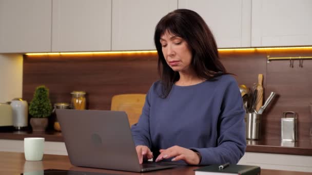 Trött äldre kvinna arbetar laptop gnuggar nacken, sträcker spända muskler, långt hårt arbete — Stockvideo