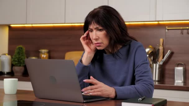 Mujer enfocada buscando portátil leyendo noticias en línea en las redes sociales en la cocina casera — Vídeos de Stock