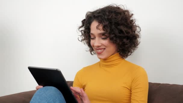 Χαμογελώντας ισπανόφωνη σγουρή γυναίκα σχεδιαστής χρησιμοποιεί το πάτημα tablet και κύλιση της οθόνης — Αρχείο Βίντεο