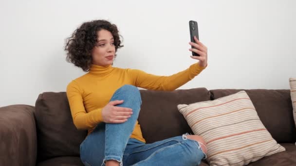 Χαμογελώντας Ισπανίδα σγουρή γυναίκα blogger χαιρετά μιλώντας σε απευθείας σύνδεση βίντεο κλήση smartphone — Αρχείο Βίντεο