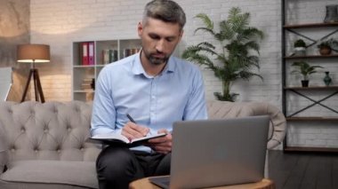 Borsacı adam yatırımcıyı internetten dinliyor, not defterine notlar yazıyor.