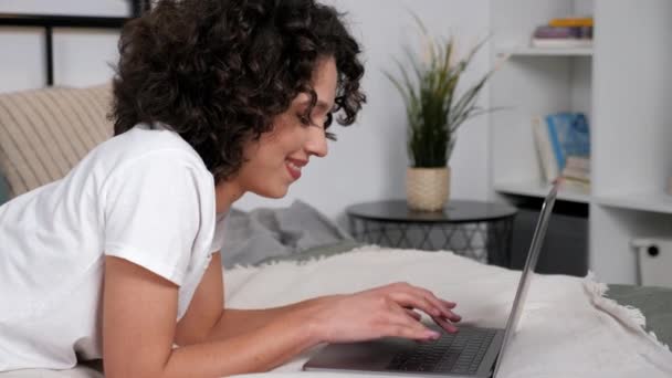 Gülümseyen kıvırcık kadın öğrenci çalışması dizüstü bilgisayar ve uzaktan eğitim kullanıyor — Stok video