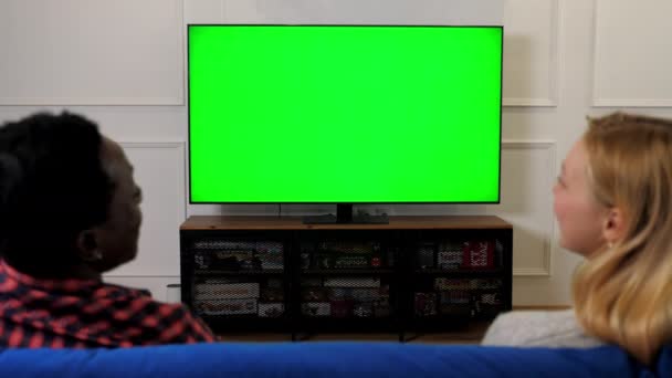 Green screen TV laughing multiethnic couple looking chroma key mock up display — Vídeo de stock