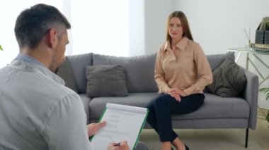 Kapalı psikoterapist klinikteki hastanın not defterine not almasını dinliyor.