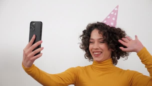 ผู้หญิงที่มีความสุขในหมวกปาร์ตี้ทักทายพูดคุยออนไลน์วิดีโอโทรสมาร์ทโฟนวันเกิด — วีดีโอสต็อก