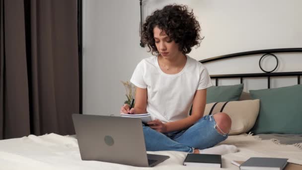 Curly woman student study online video call webcam laptop writes in notebook — Video