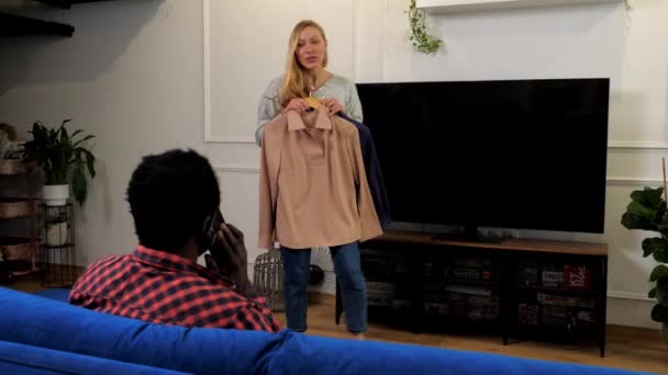 Glimlachende vrouw vraagt drukke man om advies ze kiest tussen twee blouses — Stockvideo