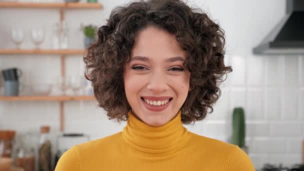 Close up face laughing hispanic curly woman looking camera at home kitchen — Vídeo de Stock