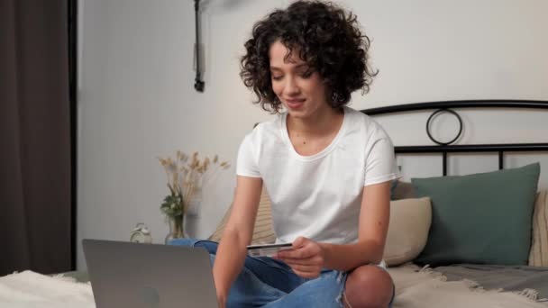 Leende kvinna skriver in kreditkortskoden för att betala gåvor, handla online via laptop — Stockvideo