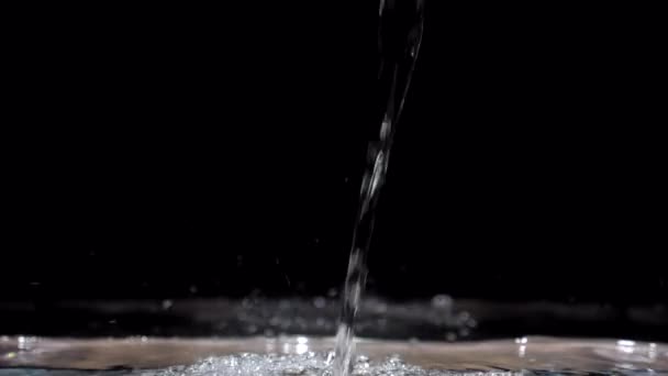 Медленное движение потока воды падает в аквариуме на черном фоне — стоковое видео
