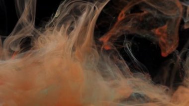 Kırmızı turuncu ve turkuaz mavi mürekkep suda karışıyor, yavaşça suyun altında dönüyor.