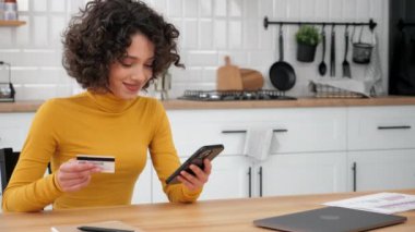 Smiling woman enters credit card code to pay gifts, online shopping smartphone