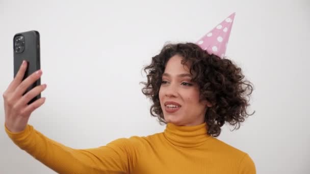 ผู้หญิงที่มีความสุขในปาร์ตี้หมวกอากาศจูบพูดคุยออนไลน์วิดีโอโทรสมาร์ทโฟนวันเกิด — วีดีโอสต็อก