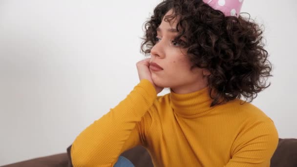 Upset woman in party hat looking away celebration holiday birthday alone at home — Stock Video