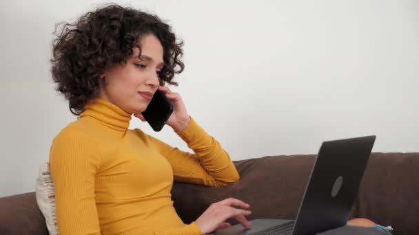 Mujer de negocios hispana sonriente hablando por teléfono móvil usando laptop en casa — Vídeos de Stock
