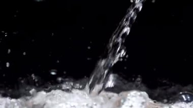Akvaryumda yavaş hareket eden su akımı siyah bir arkaplanda düşer.