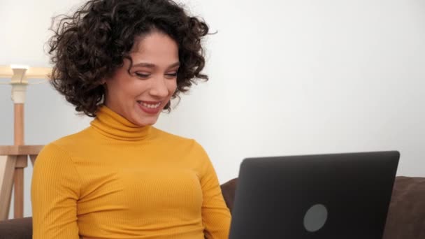 Smiling curly woman student greets talking listens online video call laptop — Vídeos de Stock