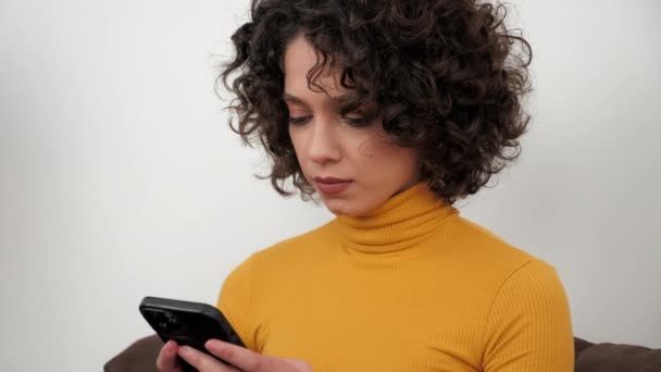 Hispanic Curly Woman Student Uses Smartphone Tapping Screen Display Sitting — Wideo stockowe