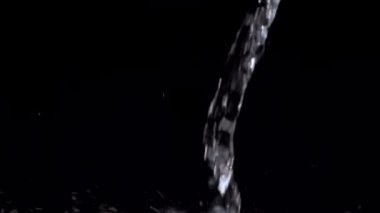 Akvaryumda yavaş hareket eden su akıntısı siyah bir zemine düşer. Yavaş çekim kristal berrak su akışı yüzeye vurur.