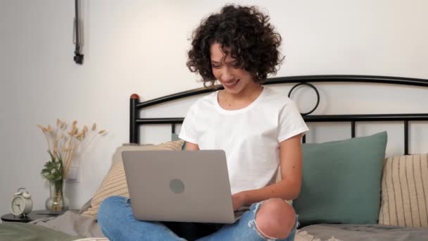 笑顔巻き女性学生の研究は ラップトップの話を聞くオンラインビデオ会議コールウェブカメラを使用しています 正のビジネス女性は 自宅でベッドに座って コンピュータのためのリモート接続チャットを通信します — ストック動画