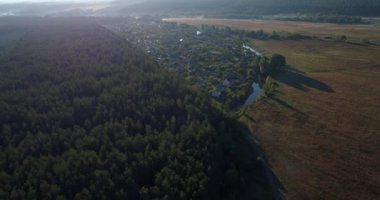 Drone aerial view a small village between forest and field at sunrise