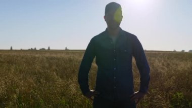 Portre gülümseyen çiftçi işadamı gün doğumunda buğday tarlasında duruyor. Buğday tarlasında kameraya bakan pozitif tarımcı adam. Tarım, tarım.