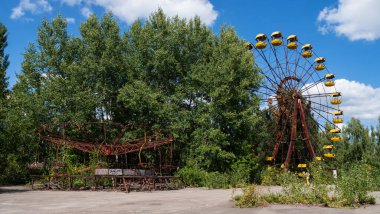 Rusty carousel and ferris wheel in ghost city Pripyat after explosion fourth reactor Chernobyl nuclear power plant. Exclusion radioactive zone on sunny summer day, Ukraine. Radiation, catastrophe