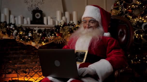 Современный Улыбающийся Санта Клаус Использует Ноутбук Заполняет Праздничные Открытки Детей — стоковое видео