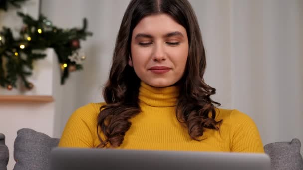 微笑的年轻女人在网上用笔记本电脑和最好的朋友聊天 漂亮的女性距离适合在舒适的家沙发上的键盘上打字 圣诞假期 — 图库视频影像