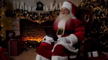 Modern gülümseyen Noel Baba çocuklara internet kameralı tablet görüntülü konferans sohbeti sunuyor. Eski mutlu Noel Baba çocuklara mutlu Noeller diliyor. Mutlu yıllar.