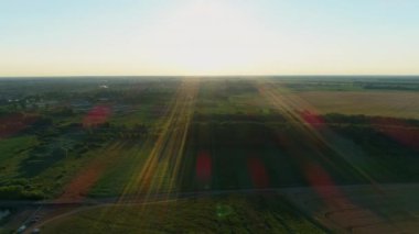 Hava manzaralı güzel yaz günbatımı ya da gün doğumu. Güneşli bir günde hava aracı sahada uçuyor. İnsansız hava aracı doğayı, manzarayı, ormanı ve buğday tarlasını vurdu
