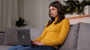 Konsantre iş kadını üst düzey yönetici şirketle çevrimiçi olarak sohbet ediyor. Güzel kadın mesafesi evdeki kanepede oturan klavyede bilgisayar daktilo metninde çalışıyor. Uzak iş toplantısı