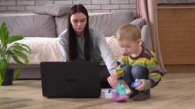 Çocuğuyla evde çalışan bir anne. Covid-19 sırasında uzaktan kumanda ve online iş. Coronavirus, Karantina, Sosyal Mesafe, Kendini İzole Etme, Tecrit, Sığınak